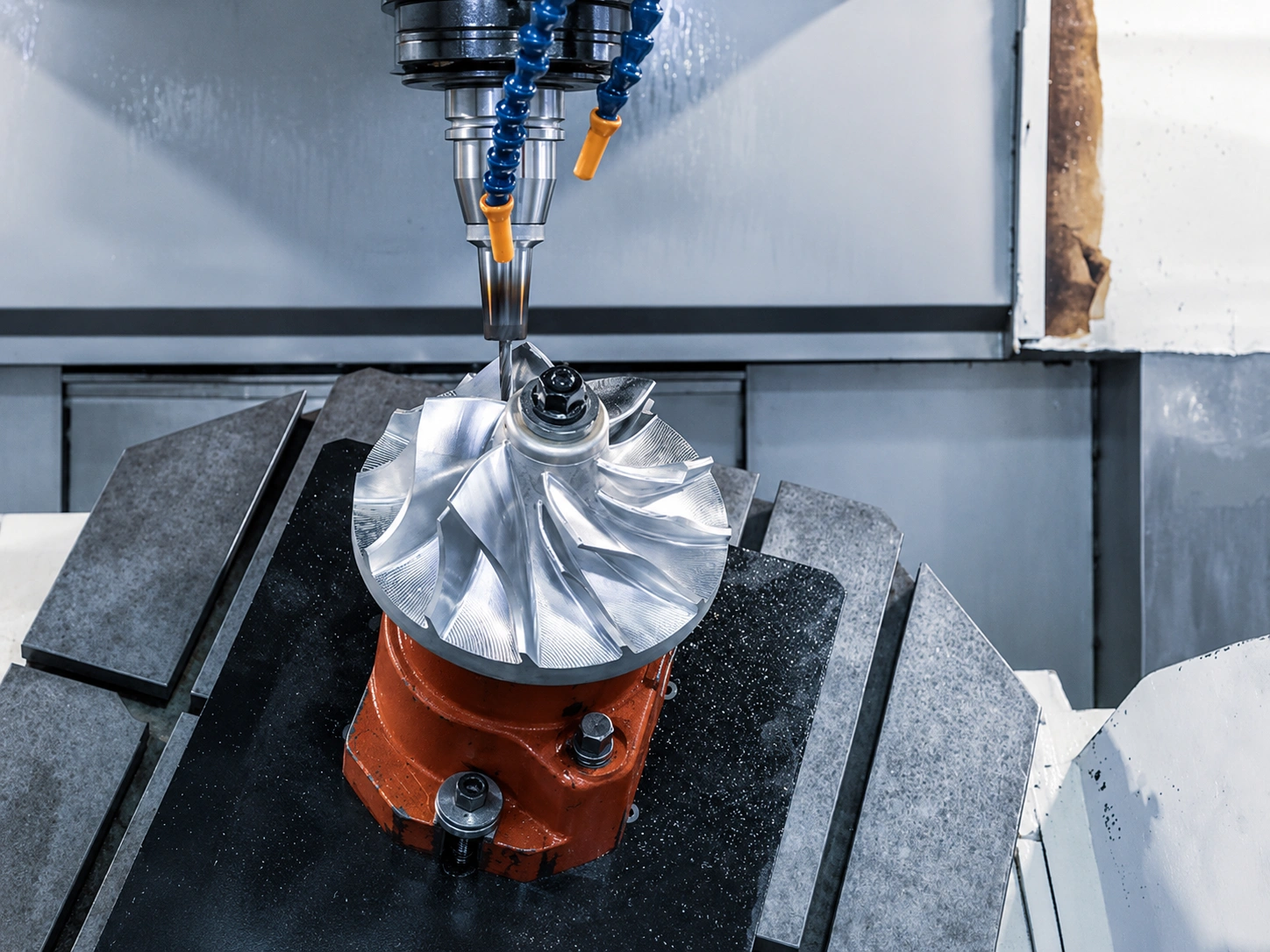 Five-axis CNC machining center cutting a high-precision jet engine turbine impeller with complex curved blades.